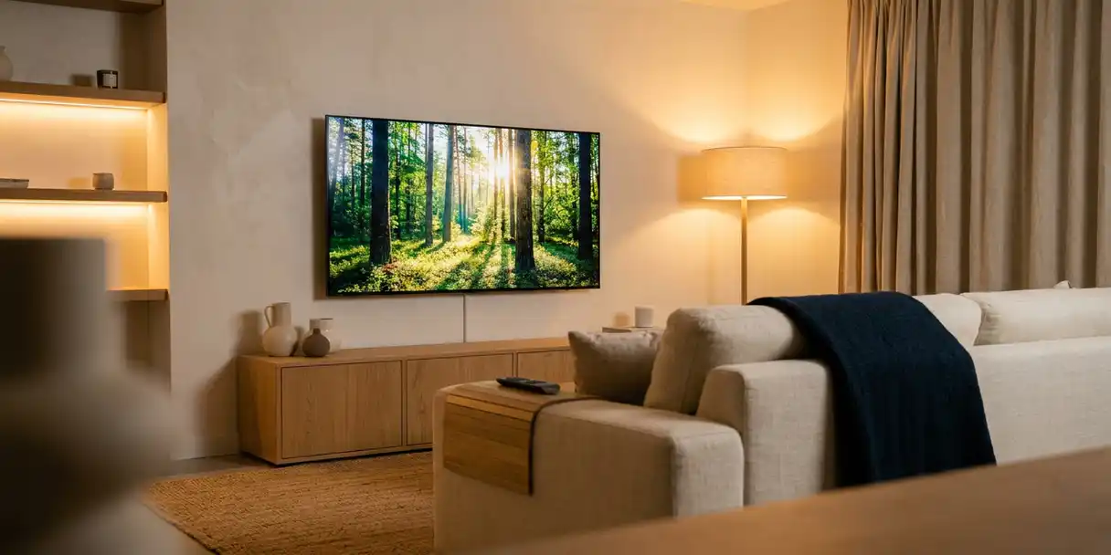 televisie-woonkamer-reclame-scandinavisch-interieur.jpg Flatscreen televisie aan de muur in een Nederlandse woonkamer met Scandinavisch interieur, eiken meubels en warme sfeerverlichting.