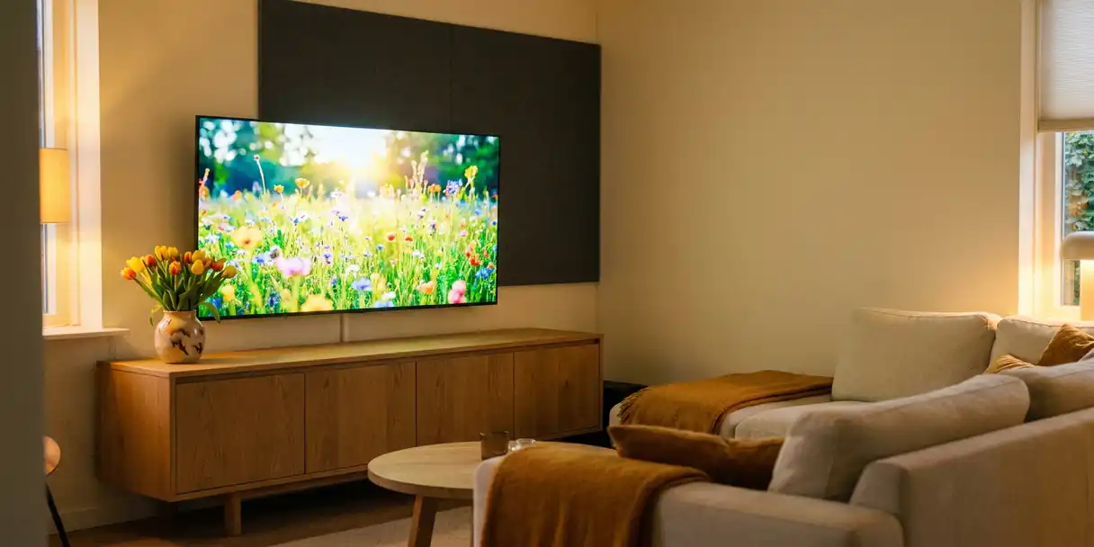 Flatscreen tv aan de muur in een moderne Nederlandse woonkamer met eiken meubels, tulpen en warme avondverlichting.